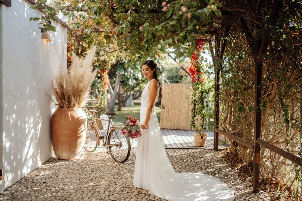 Novia con maquillaje radiante posando en un patio de estilo mediterráneo el día de su boda en Valencia.